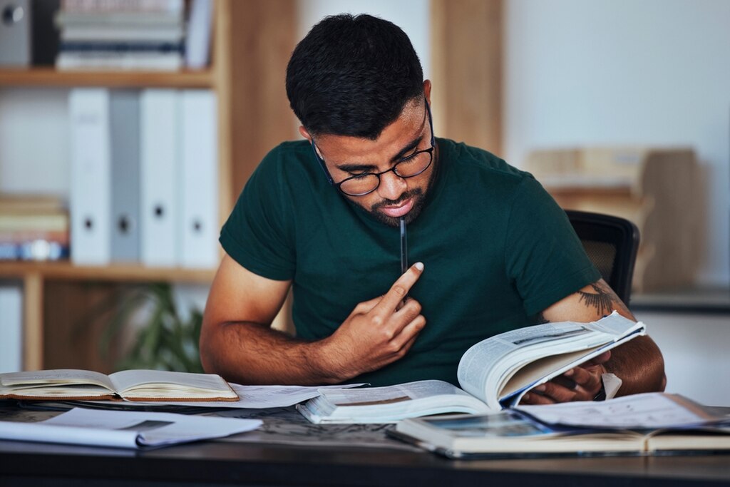 homem estudando sentado com livros abertos